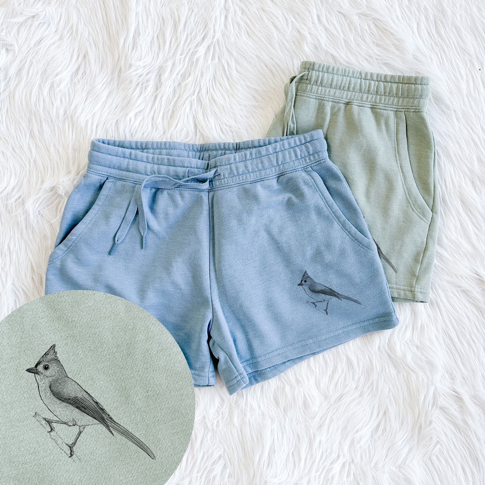 Two pairs of Cali Wave shorts in different colors printed with a detailed black ink sketch of a tufted titmouse perched on a branch, with a close-up of the print.