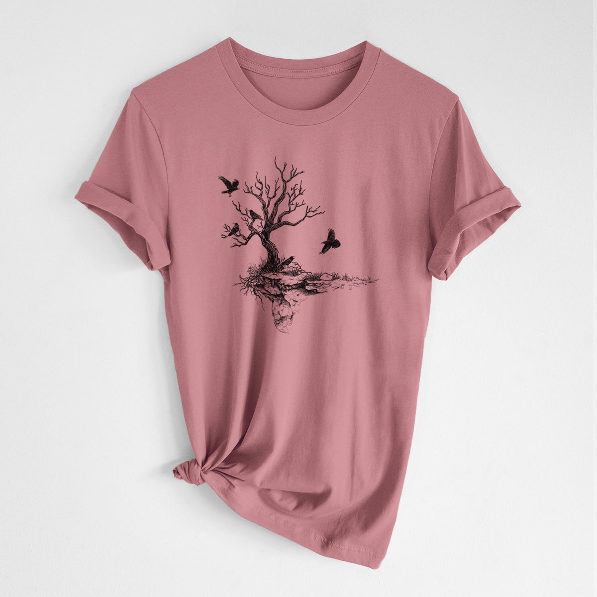 Mauve pink lightweight cotton t-shirt laid flat with the sleeves rolled, printed with a black ink illustration of a bare twisted tree on a small island with ravens flying around it.