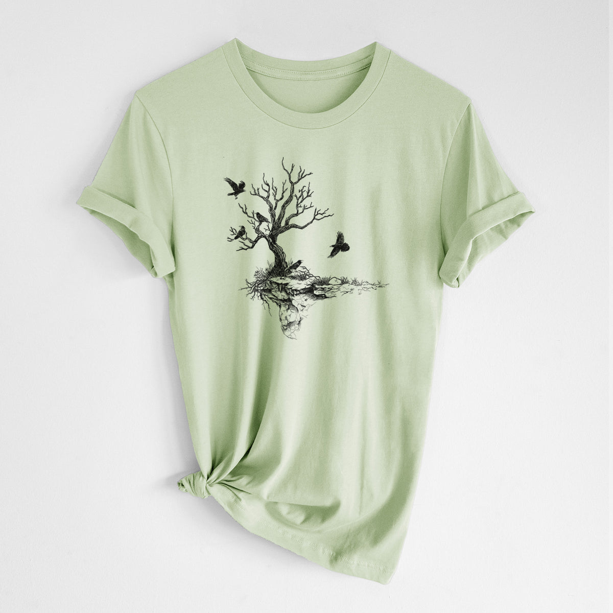 Spring green lightweight cotton t-shirt laid flat with the sleeves rolled, printed with a black ink illustration of a bare twisted tree on a small island with ravens flying around it.