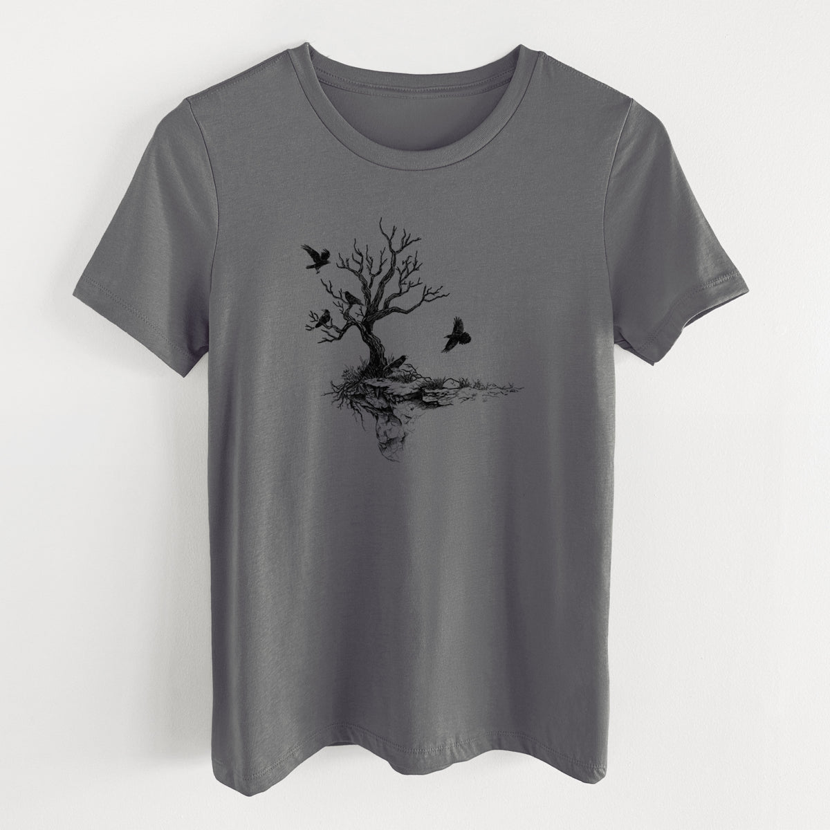 Asphalt women's relaxed fit cotton t-shirt laid flat, printed with a black ink illustration of a bare twisted tree on a small island with ravens flying around it.