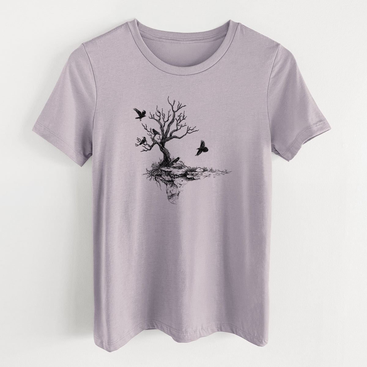 Light violet women's relaxed fit cotton t-shirt laid flat, printed with a black ink illustration of a bare twisted tree on a small island with ravens flying around it.