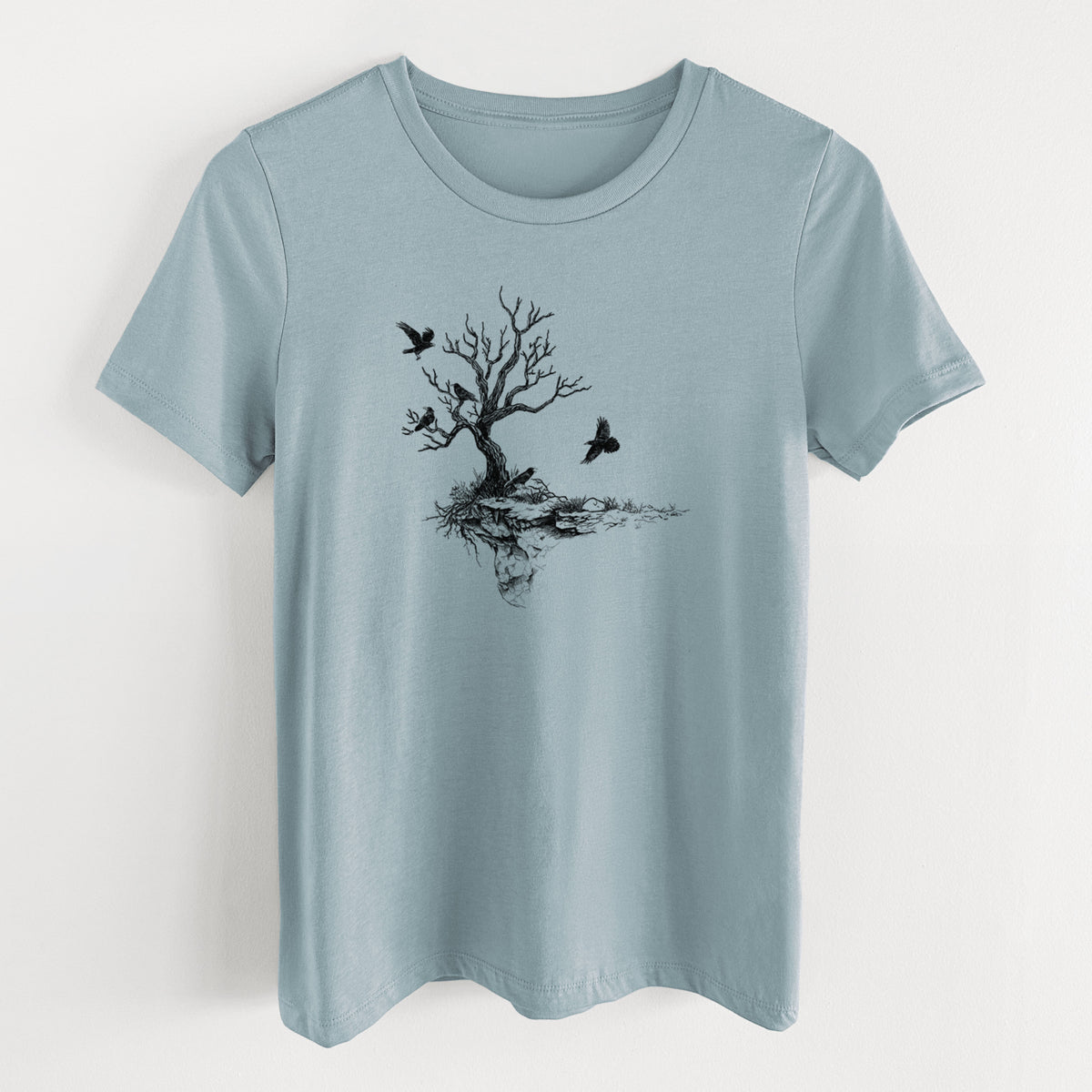 Vintage denim women's relaxed fit cotton t-shirt laid flat, printed with a black ink illustration of a bare twisted tree on a small island with ravens flying around it.