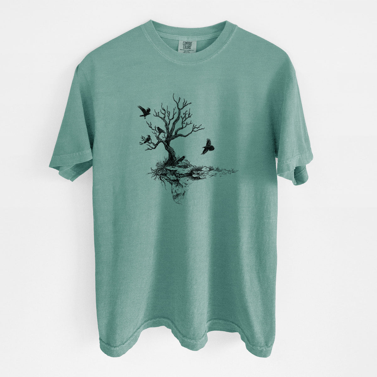 Reef green Comfort Colors t-shirt laid flat, printed with a black ink illustration of a bare twisted tree on a small island with ravens flying around it.