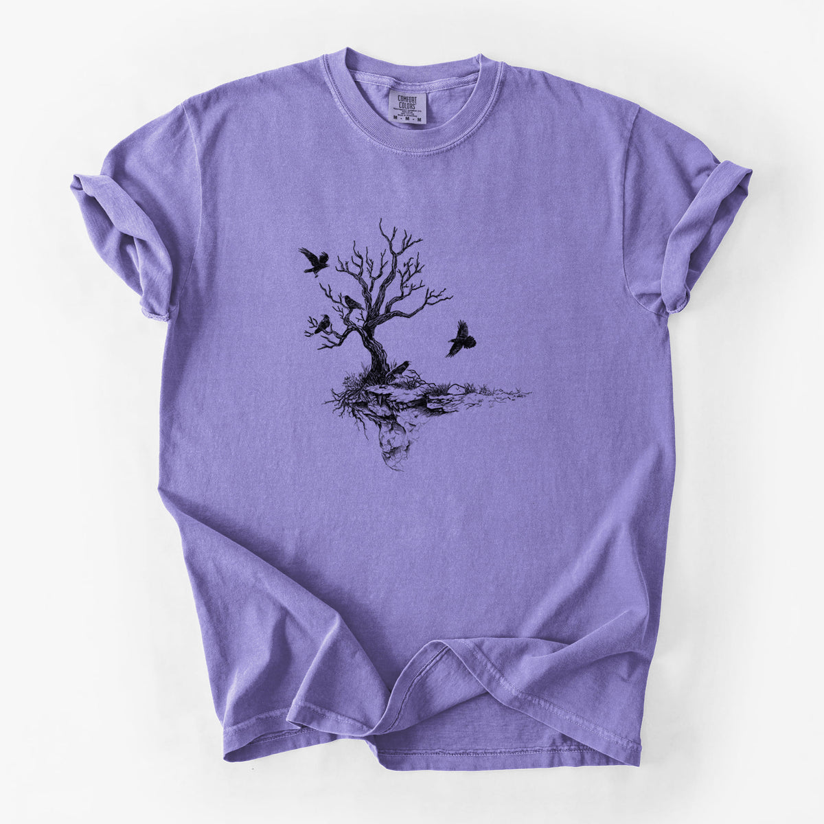 Violet purple Comfort Colors t-shirt laid flat, printed with a black ink illustration of a bare twisted tree on a small island with ravens flying around it.