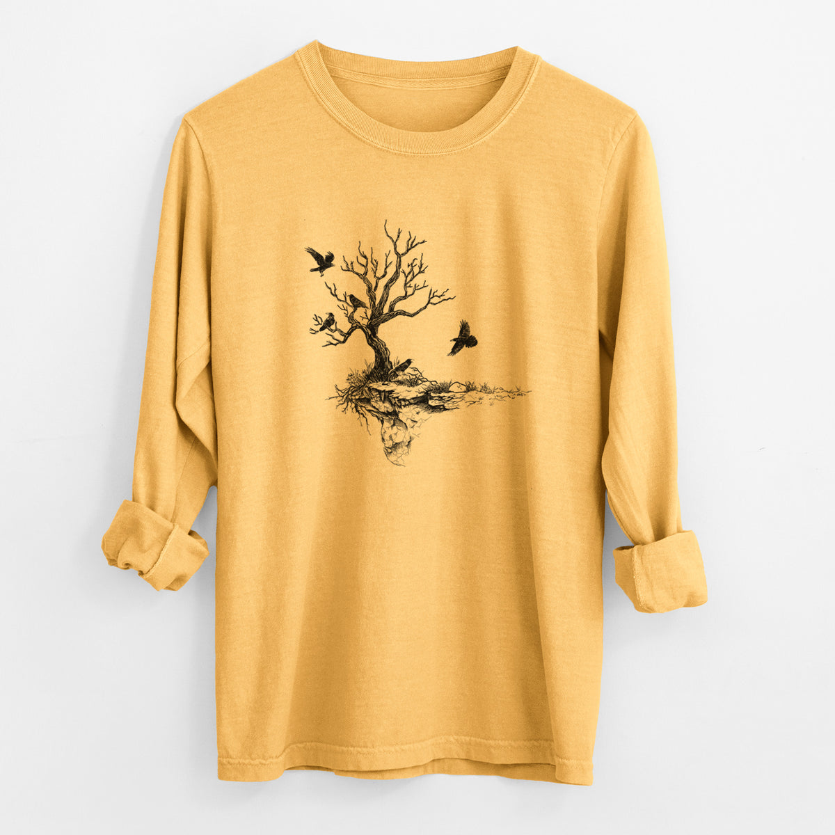 Golden wheat yellow Comfort Colors long sleeve shirt laid flat with the cuffs rolled, printed with a black ink illustration of a bare twisted tree on a small island with ravens flying around it.