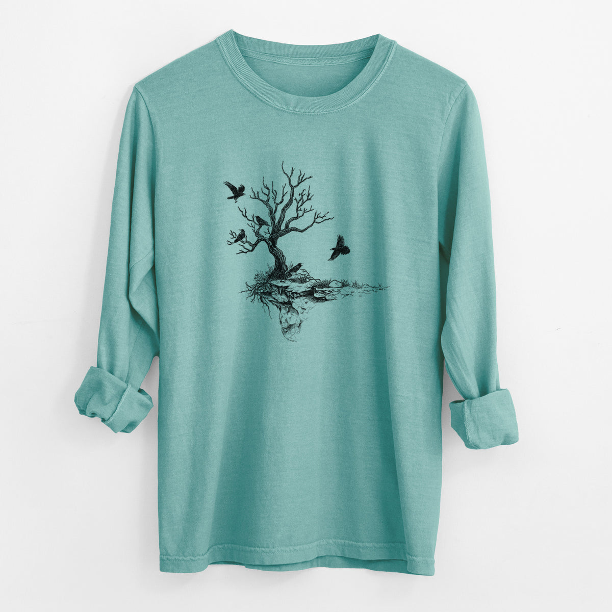 Reef green Comfort Colors long sleeve shirt laid flat with the cuffs rolled, printed with a black ink illustration of a bare twisted tree on a small island with ravens flying around it.
