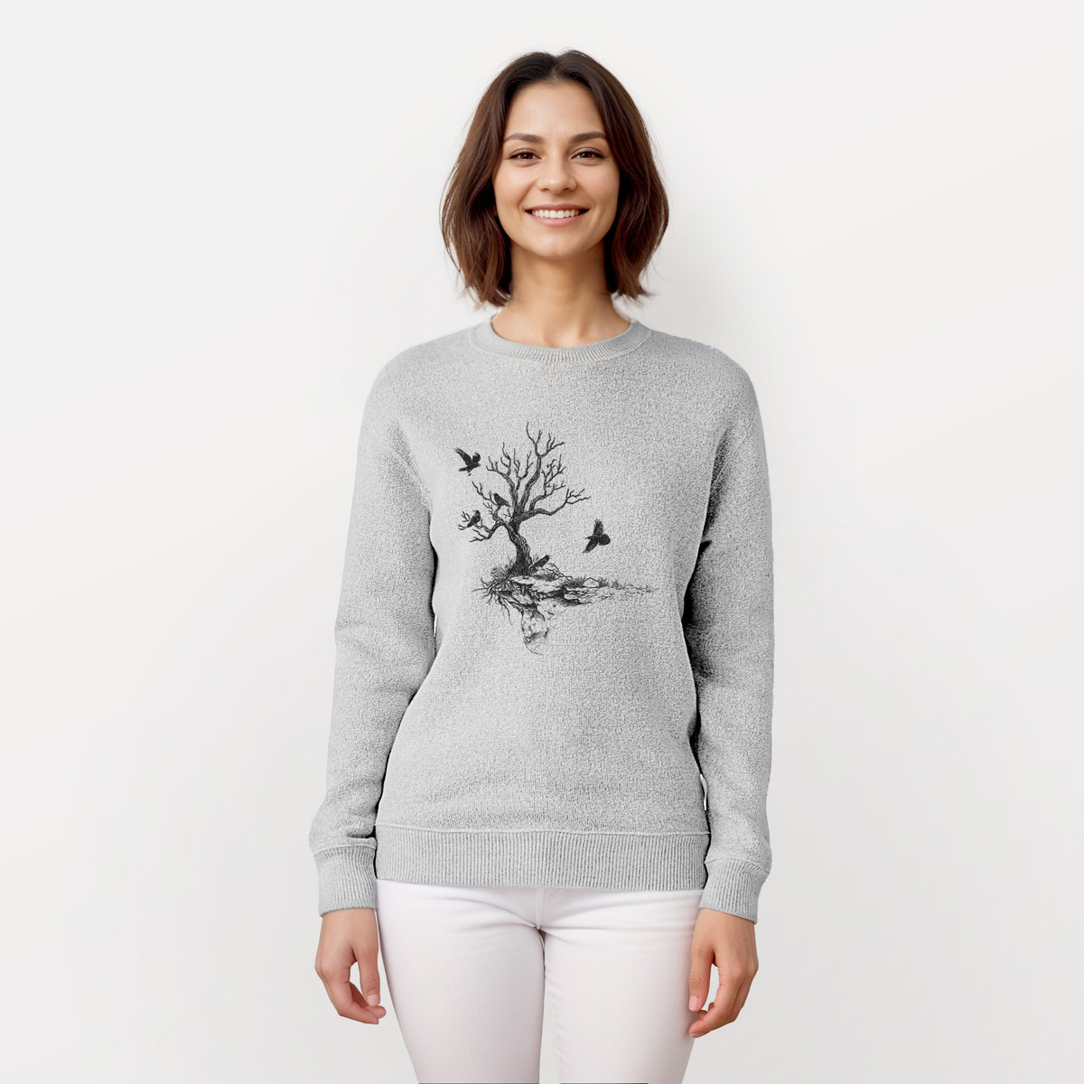 Woman wearing a knit sweatshirt printed with a black ink illustration of a bare twisted tree on a small island with ravens flying around it.