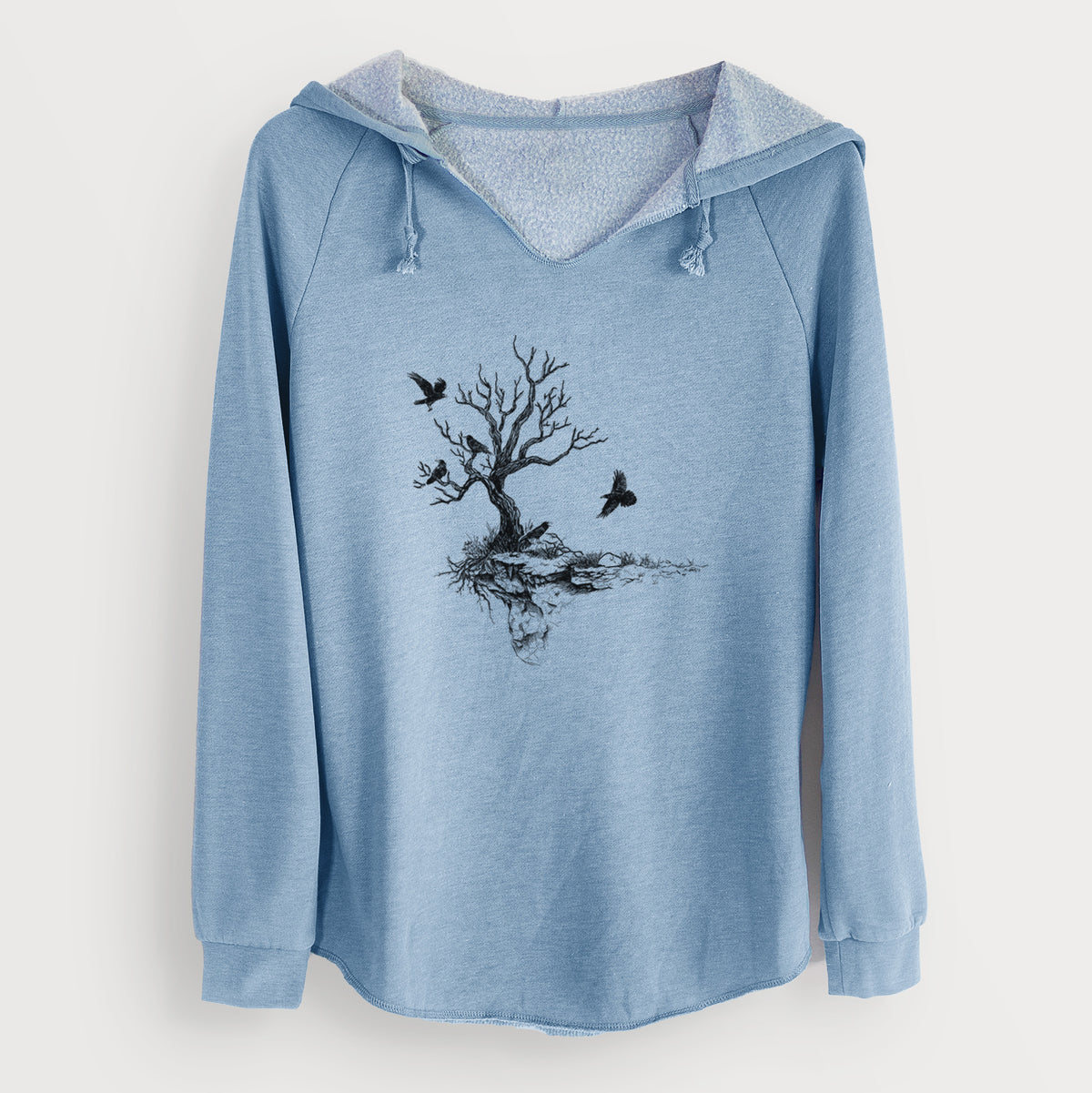 Misty blue women's Cali Wave hooded sweatshirt laid flat, printed with a black ink illustration of a bare twisted tree on a small island with ravens flying around it.