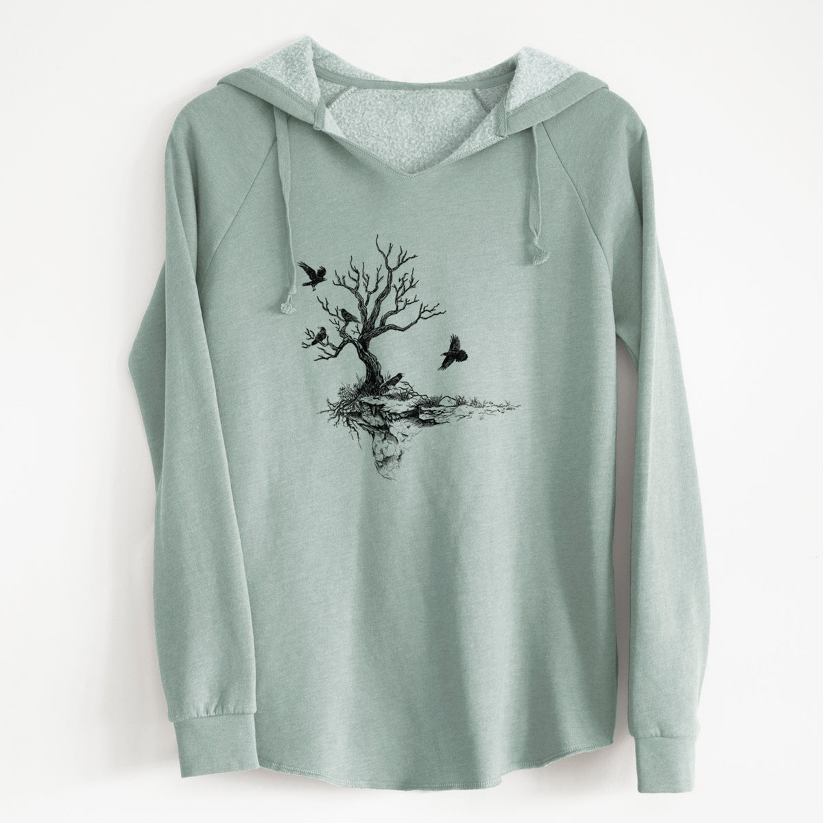 Sage green women's Cali Wave hooded sweatshirt laid flat, printed with a black ink illustration of a bare twisted tree on a small island with ravens flying around it.