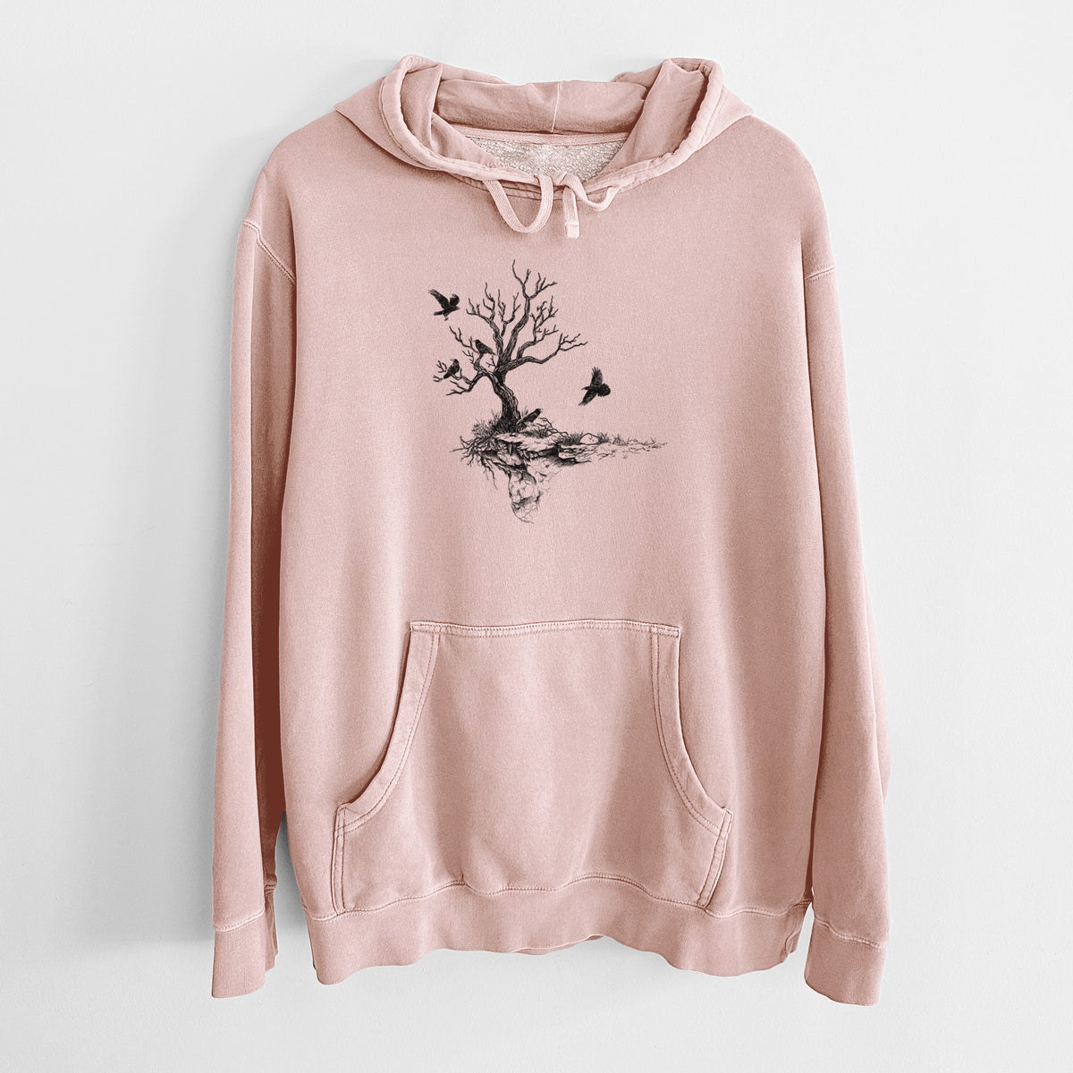 Dusty pink pigment dyed hoodie laid flat, printed with a black ink illustration of a bare twisted tree on a small island with ravens flying around it.