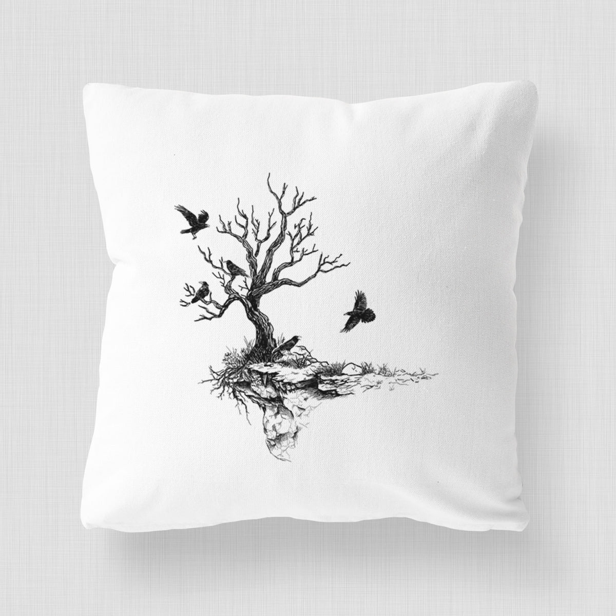 White pillow cover printed with a black ink illustration of a bare twisted tree on a small island with ravens flying around it.