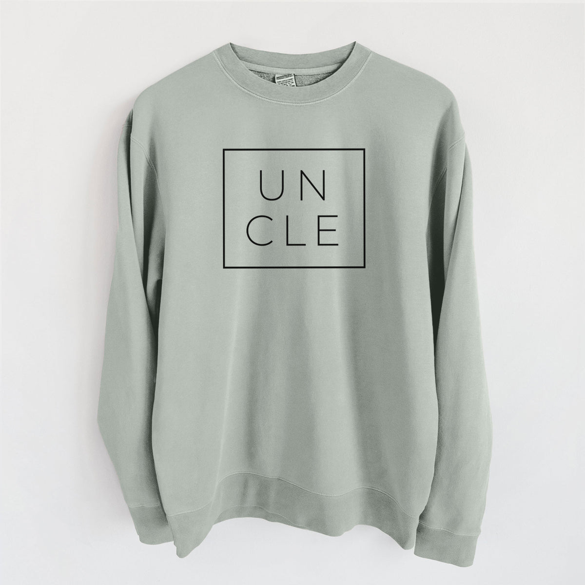 Sage green pigment dyed crewneck sweatshirt laid flat, printed with the word UNCLE in thin black letters stacked inside a square outline.