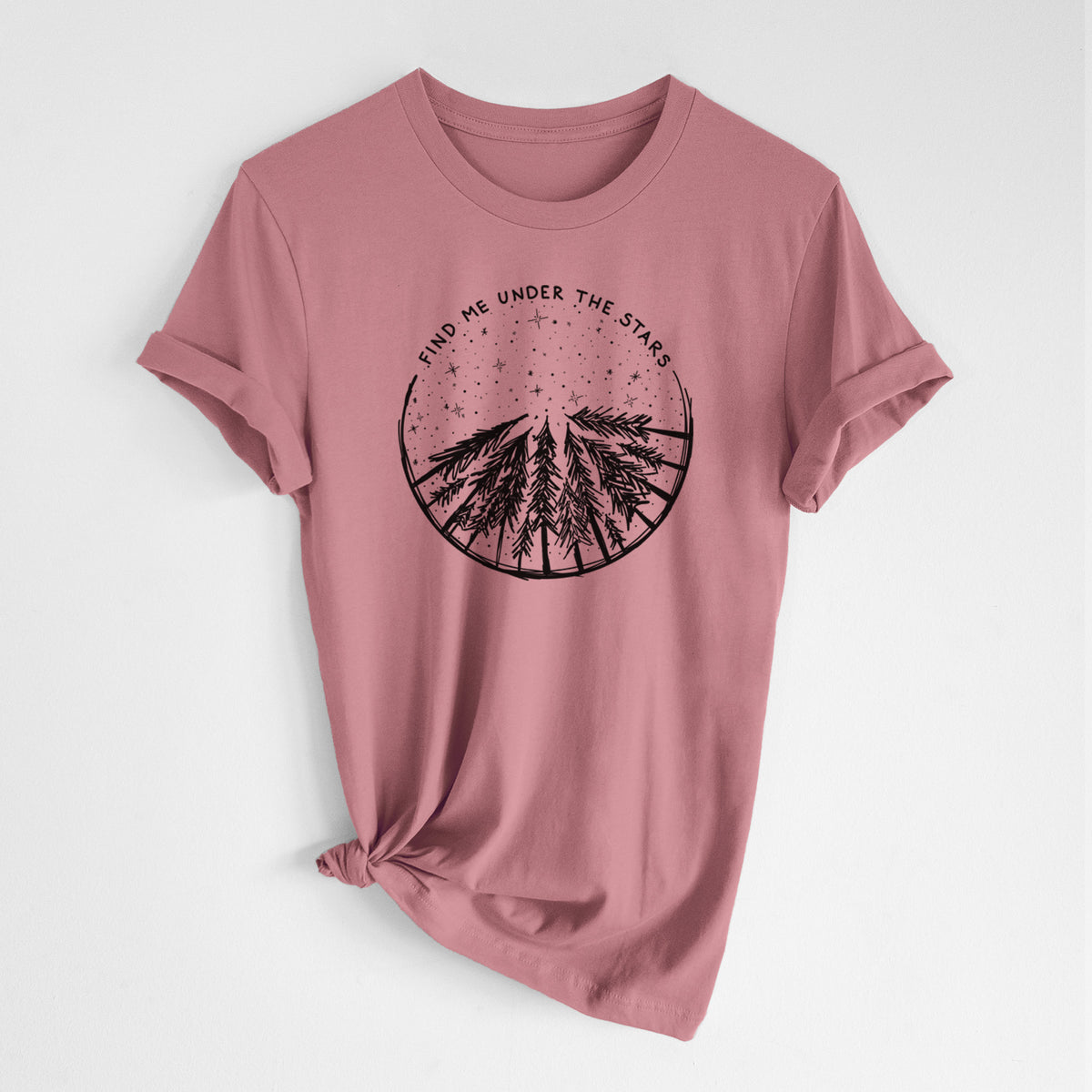 Mauve pink lightweight cotton t-shirt laid flat with the sleeves rolled, printed with a circle of pine trees under a starry sky, with the words Find Me Under the Stars.