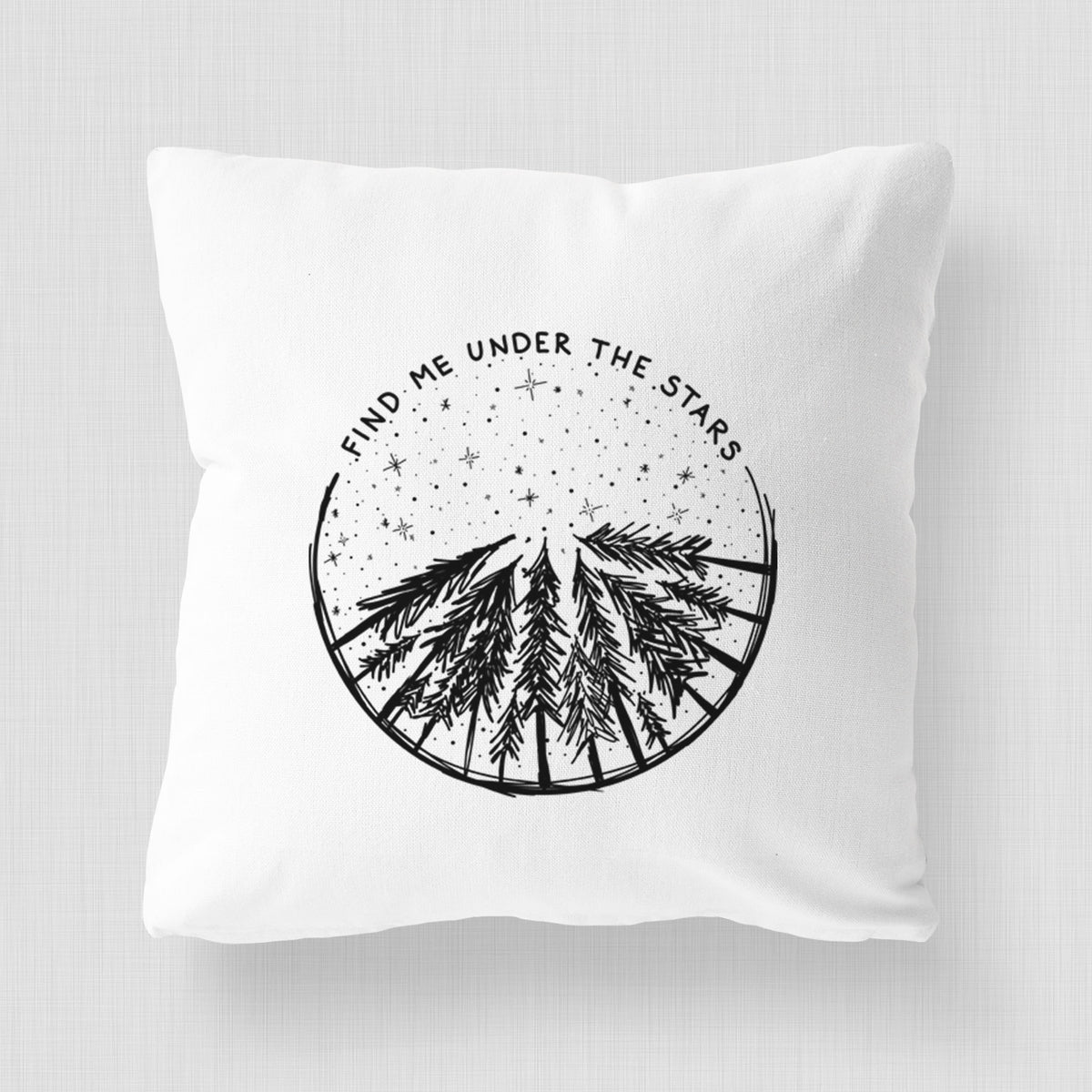 White pillow cover printed with a circle of pine trees under a starry sky, with the words Find Me Under the Stars.
