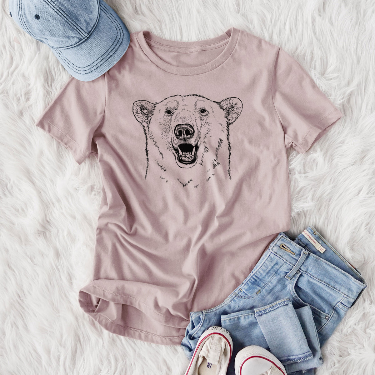 Women's relaxed fit cotton t-shirt printed with a black ink portrait of a smiling polar bear's face, styled flat on a white faux fur rug with jeans.