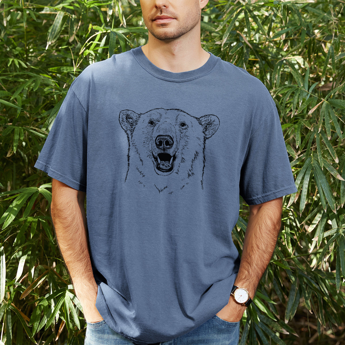 Man wearing a Comfort Colors t-shirt printed with a black ink portrait of a smiling polar bear's face, outdoors.