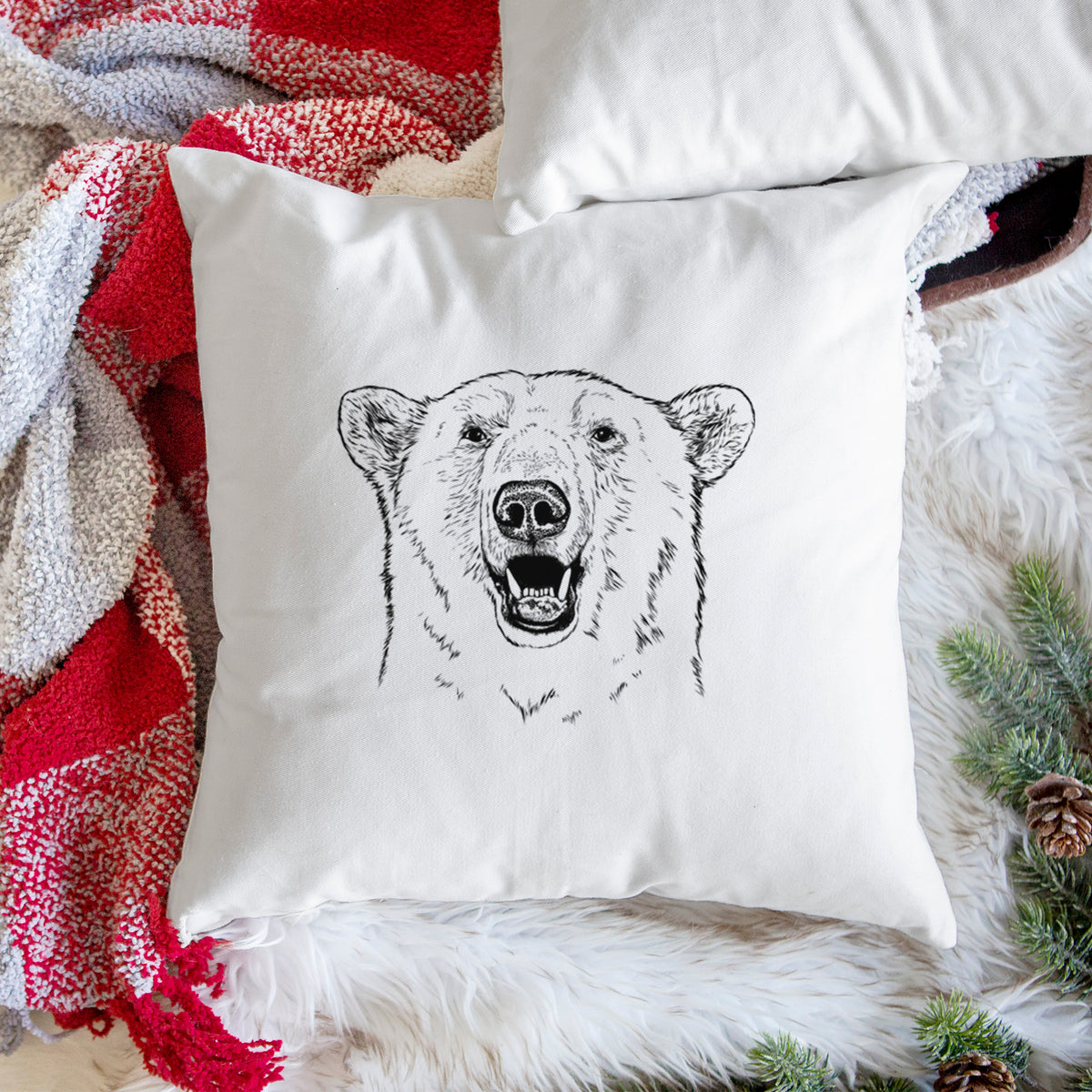White pillow cover printed with a black ink portrait of a smiling polar bear's face, on a woven chair.