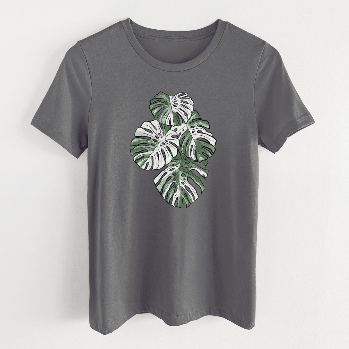 Asphalt women's relaxed fit cotton t-shirt laid flat, printed with a full-color illustration of a variegated Monstera leaf in green and white.