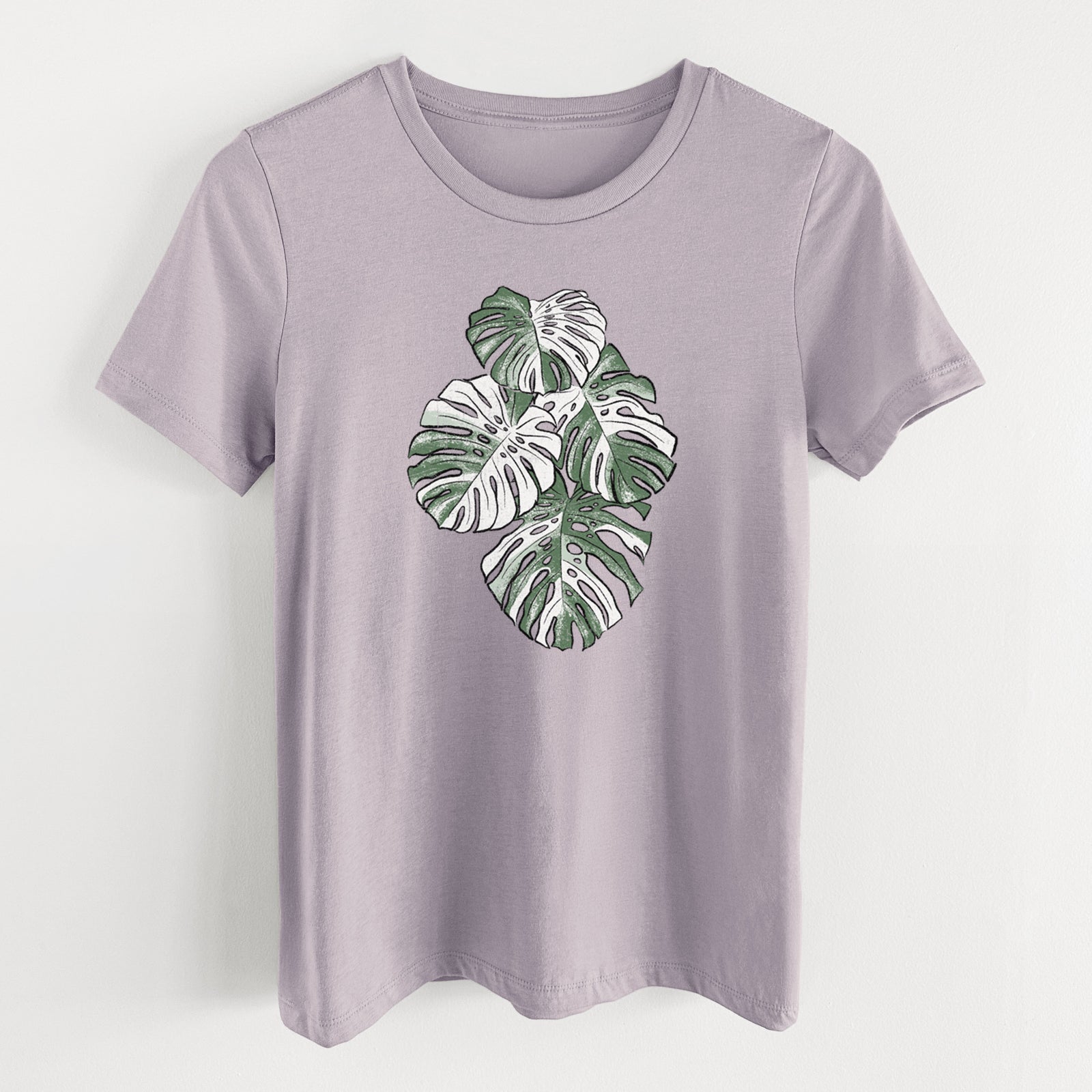 Light violet women's relaxed fit cotton t-shirt laid flat, printed with a full-color illustration of a variegated Monstera leaf in green and white.