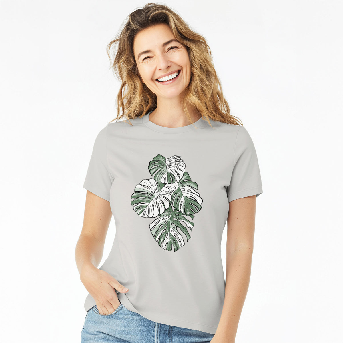 Woman wearing a lunar grey women's relaxed fit cotton t-shirt printed with a full-color illustration of a variegated Monstera leaf in green and white.