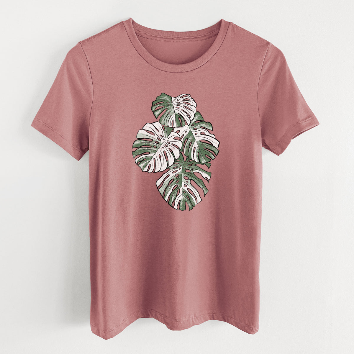 Mauve pink women's relaxed fit cotton t-shirt laid flat, printed with a full-color illustration of a variegated Monstera leaf in green and white.