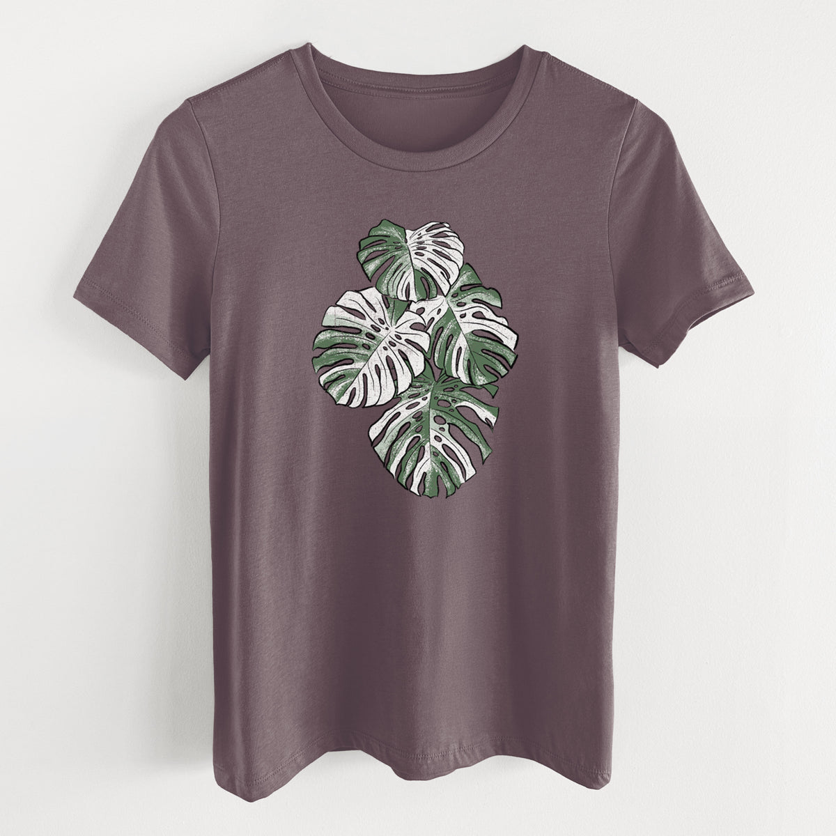 Purple storm women's relaxed fit cotton t-shirt laid flat, printed with a full-color illustration of a variegated Monstera leaf in green and white.