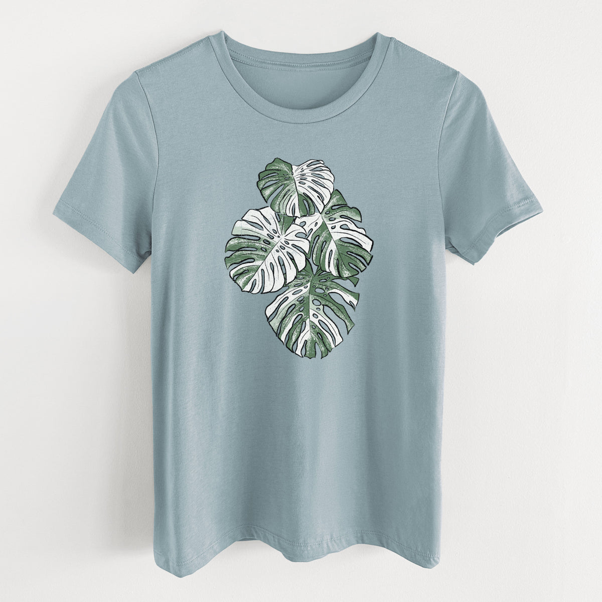 Vintage denim women's relaxed fit cotton t-shirt laid flat, printed with a full-color illustration of a variegated Monstera leaf in green and white.