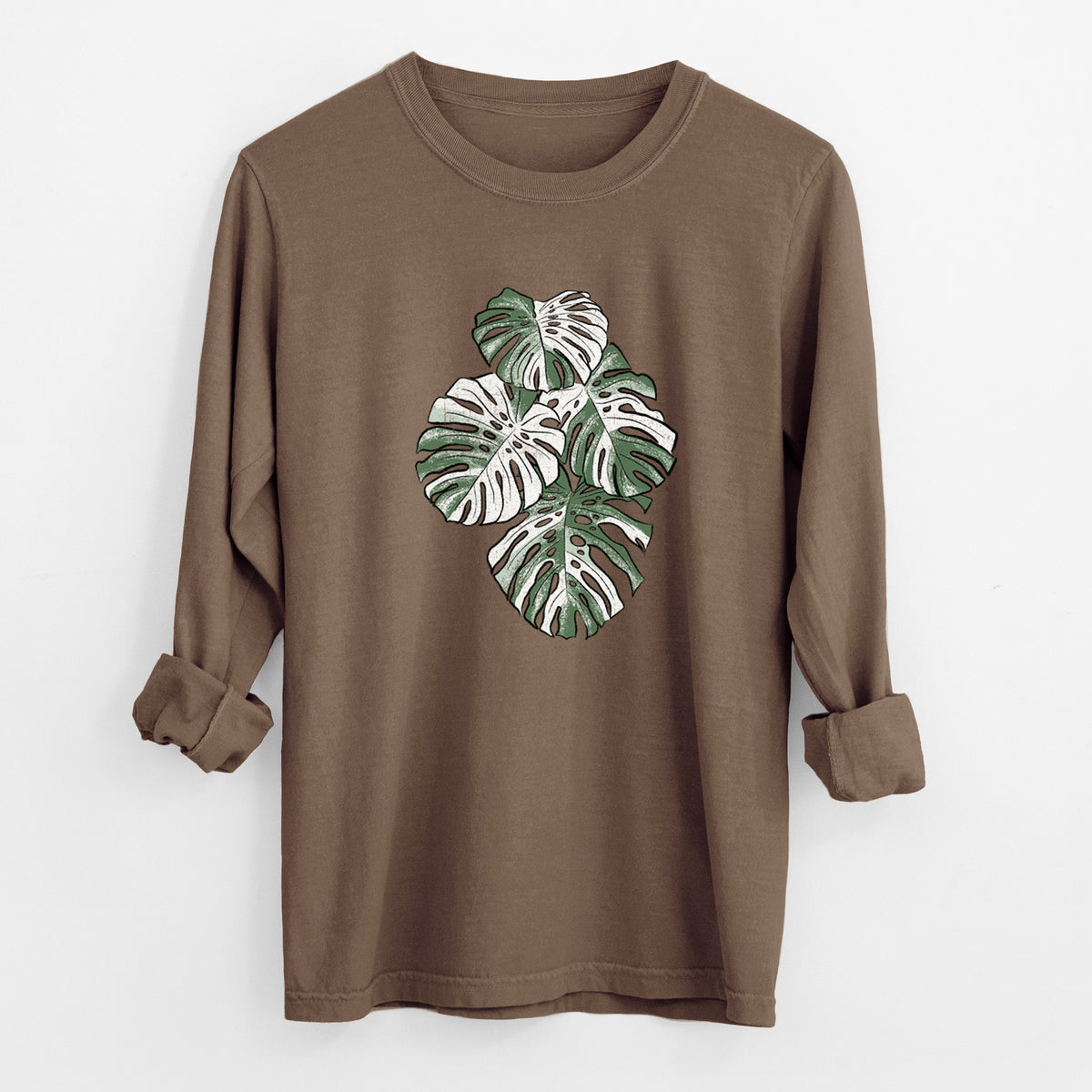 Espresso brown Comfort Colors long sleeve shirt laid flat with the cuffs rolled, printed with a full-color illustration of a variegated Monstera leaf in green and white.