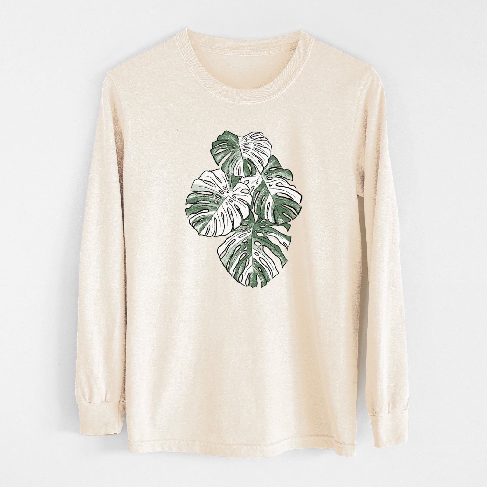Ivory Comfort Colors long sleeve shirt laid flat, printed with a full-color illustration of a variegated Monstera leaf in green and white.