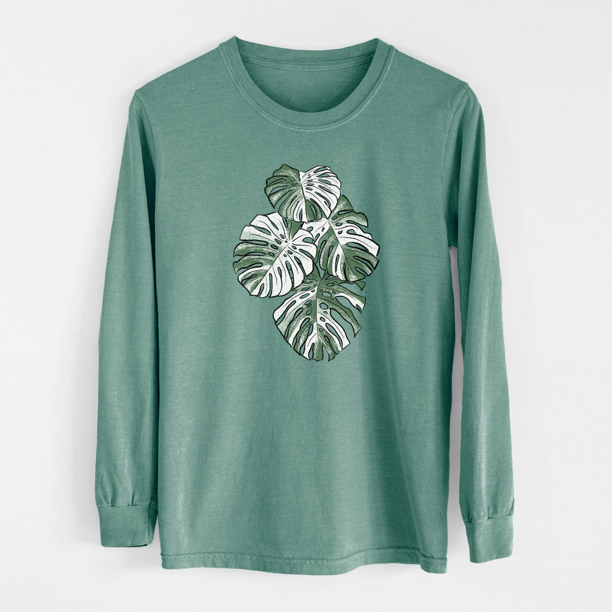Pine green Comfort Colors long sleeve shirt laid flat, printed with a full-color illustration of a variegated Monstera leaf in green and white.