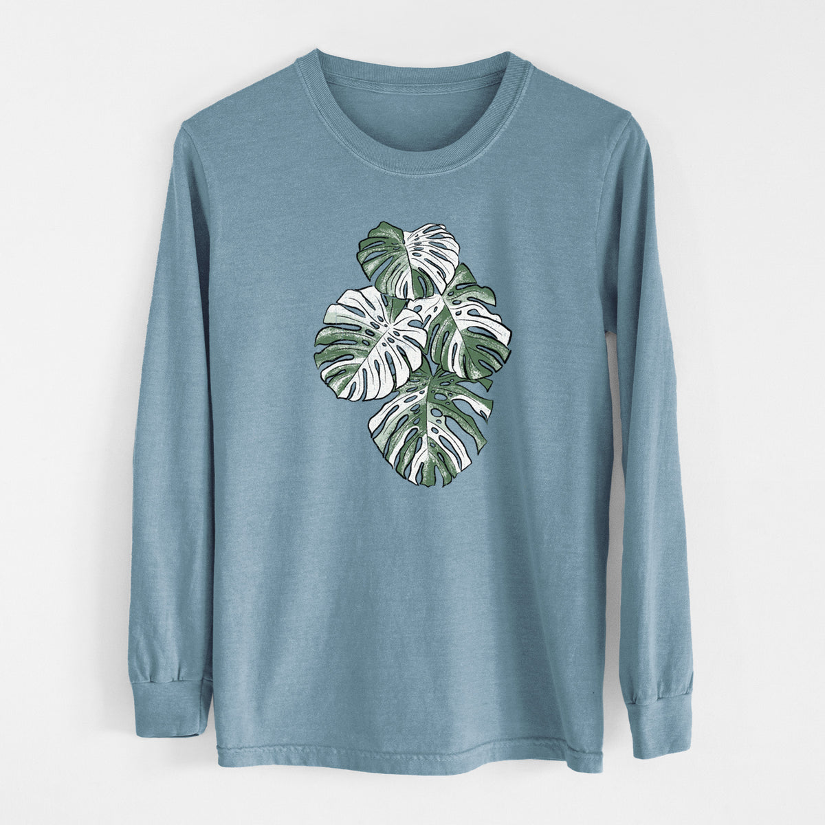 Steel blue Comfort Colors long sleeve shirt laid flat, printed with a full-color illustration of a variegated Monstera leaf in green and white.