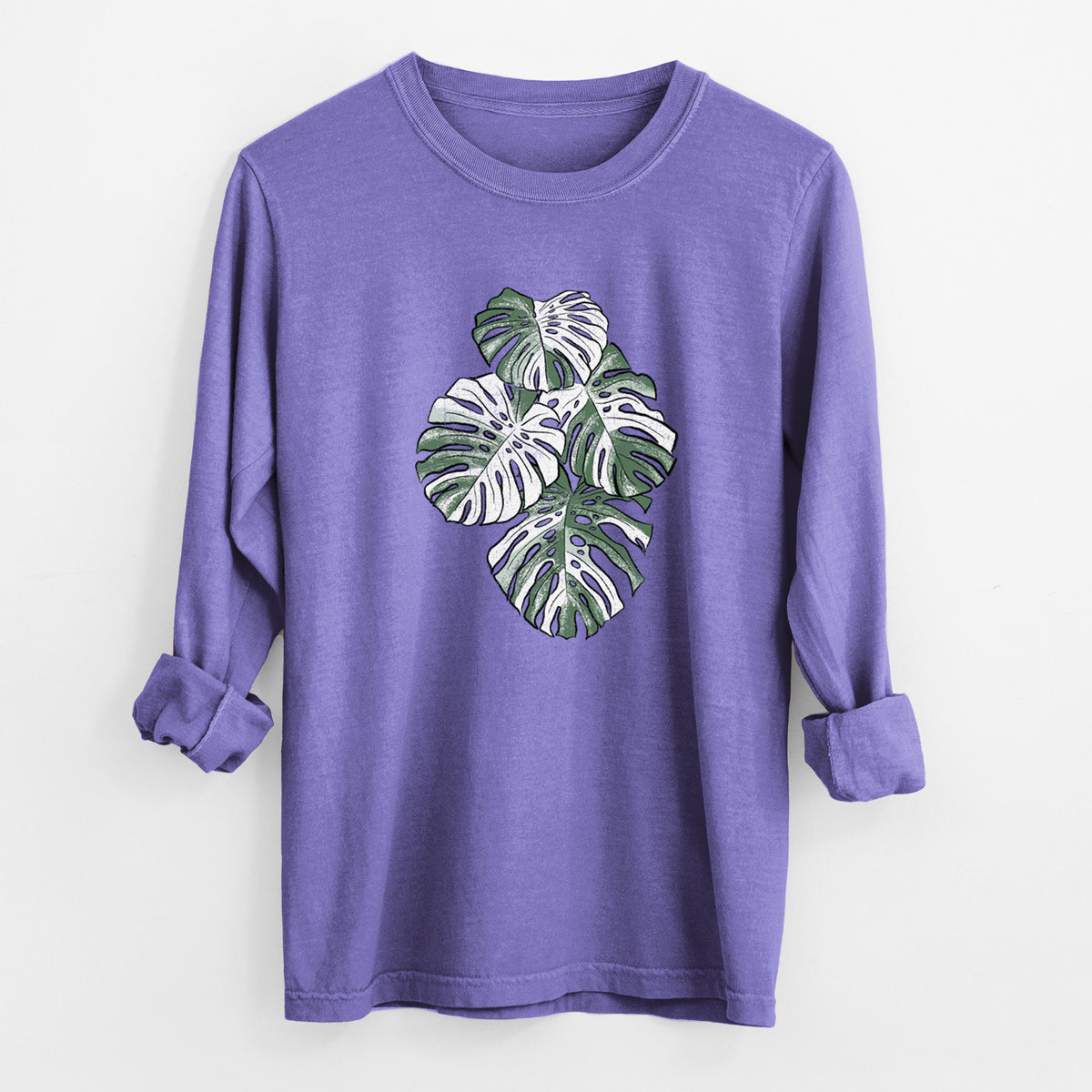 Violet purple Comfort Colors long sleeve shirt laid flat with the cuffs rolled, printed with a full-color illustration of a variegated Monstera leaf in green and white.