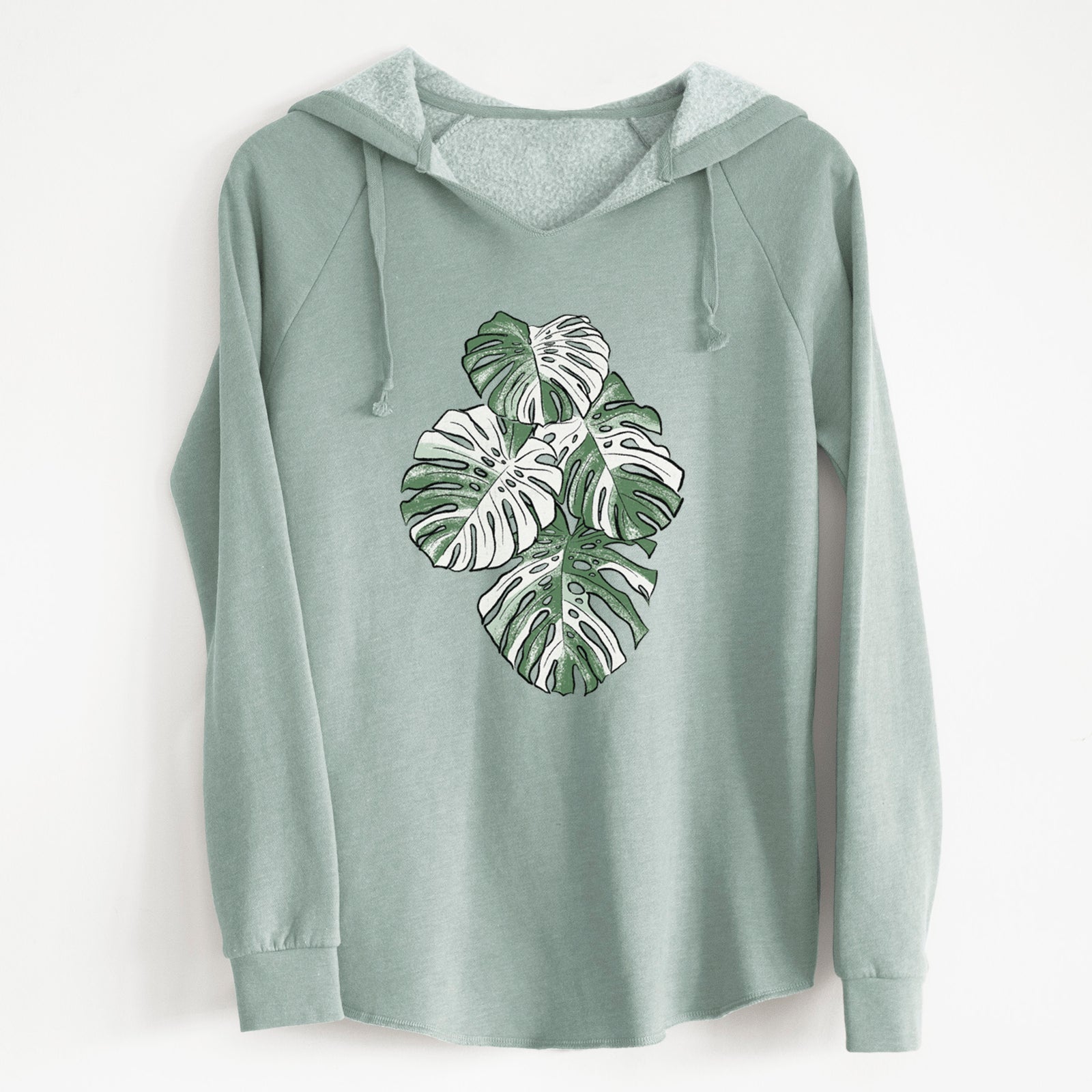 Sage green women's Cali Wave hooded sweatshirt laid flat, printed with a full-color illustration of a variegated Monstera leaf in green and white.