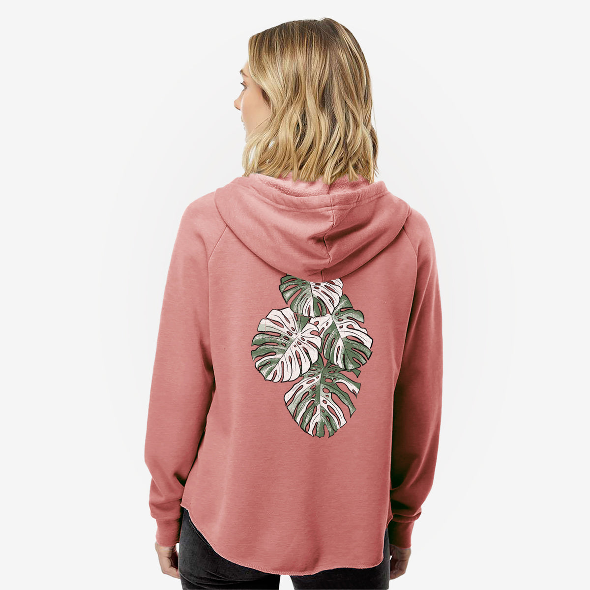 Woman wearing a dusty rose women's Cali Wave zip-up sweatshirt printed with a full-color illustration of a variegated Monstera leaf in green and white, seen from behind.