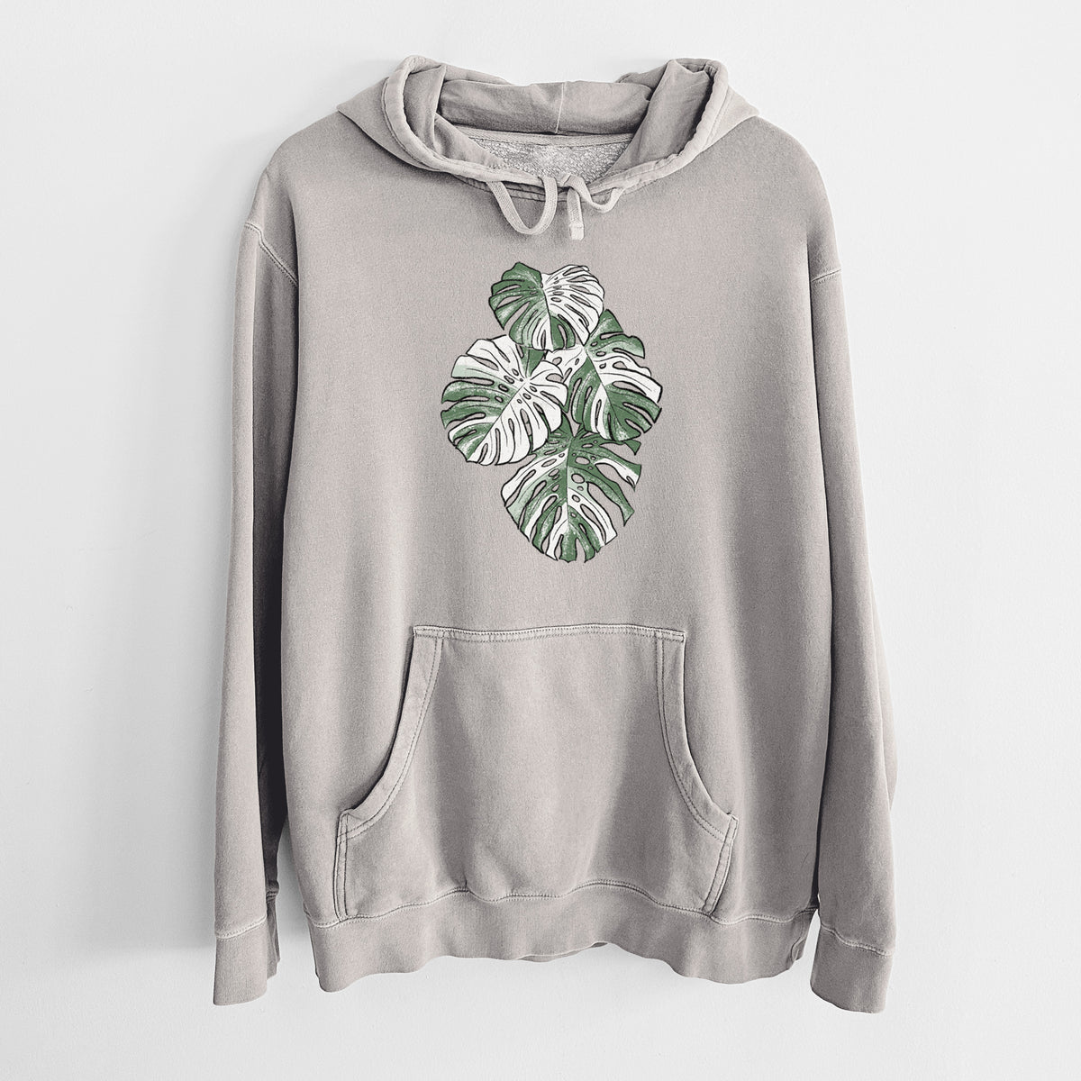 Cement grey pigment dyed hoodie laid flat, printed with a full-color illustration of a variegated Monstera leaf in green and white.