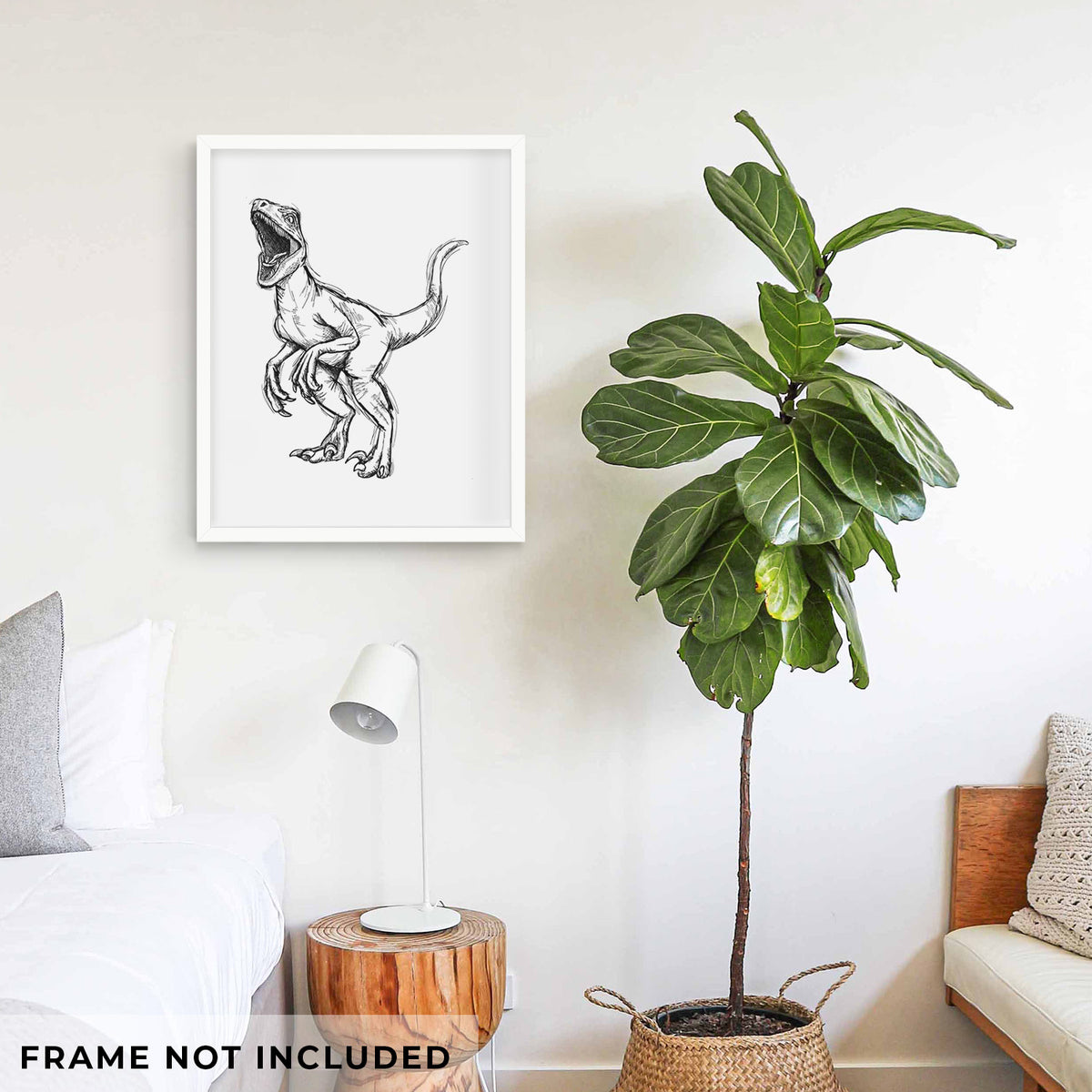 Art print of a black ink illustration of a Velociraptor roaring, shown framed on a living room wall beside a potted plant. Frame not included.