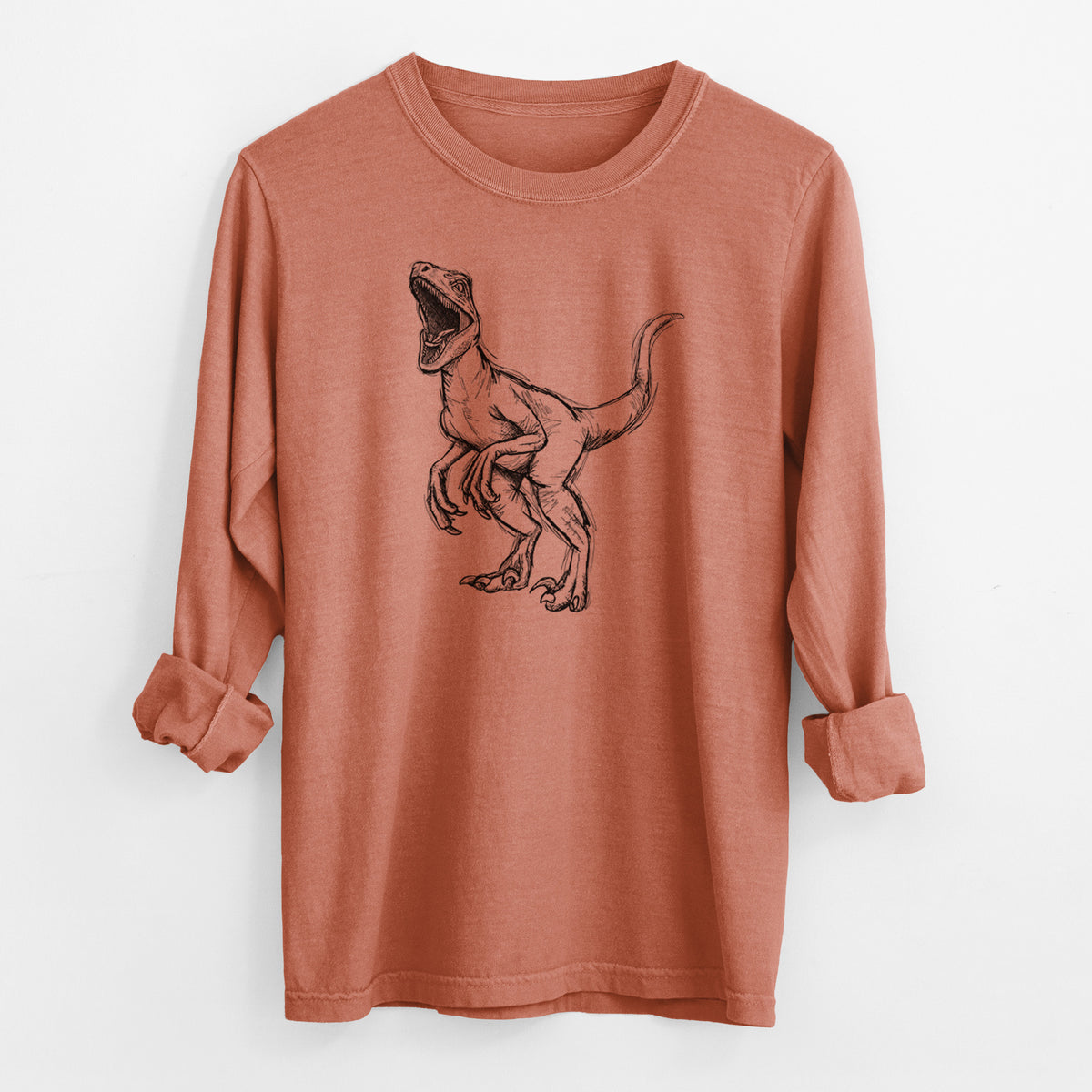 Yam burnt orange Comfort Colors long sleeve shirt laid flat with the cuffs rolled, printed with a black ink illustration of a Velociraptor roaring.