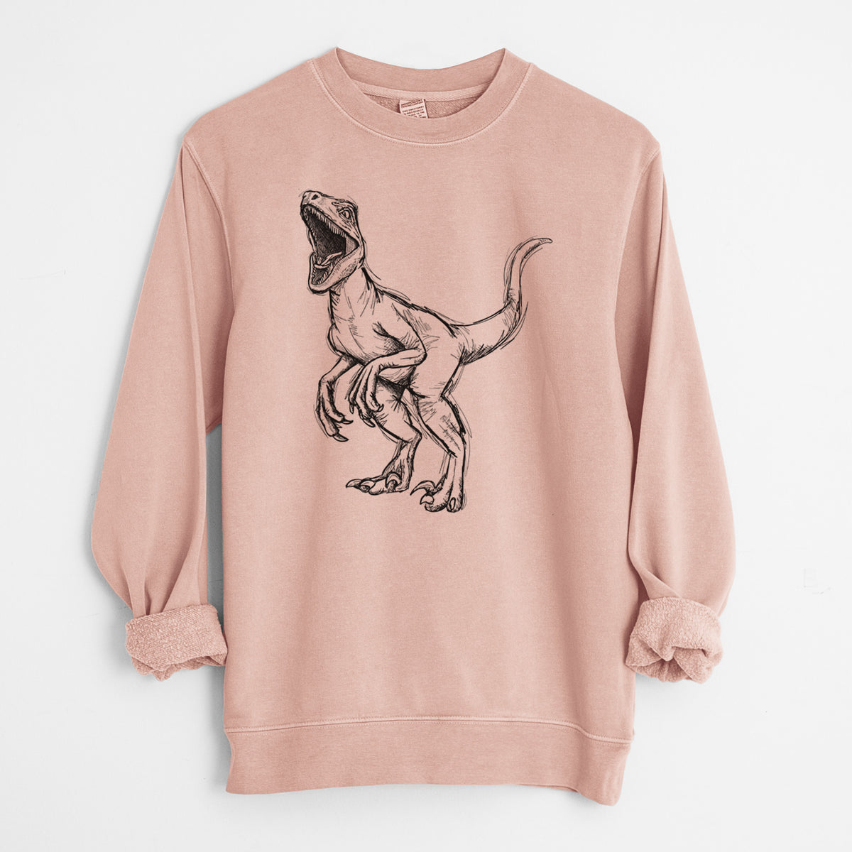 Dusty pink pigment dyed crewneck sweatshirt laid flat with the sleeves rolled, printed with a black ink illustration of a Velociraptor roaring.