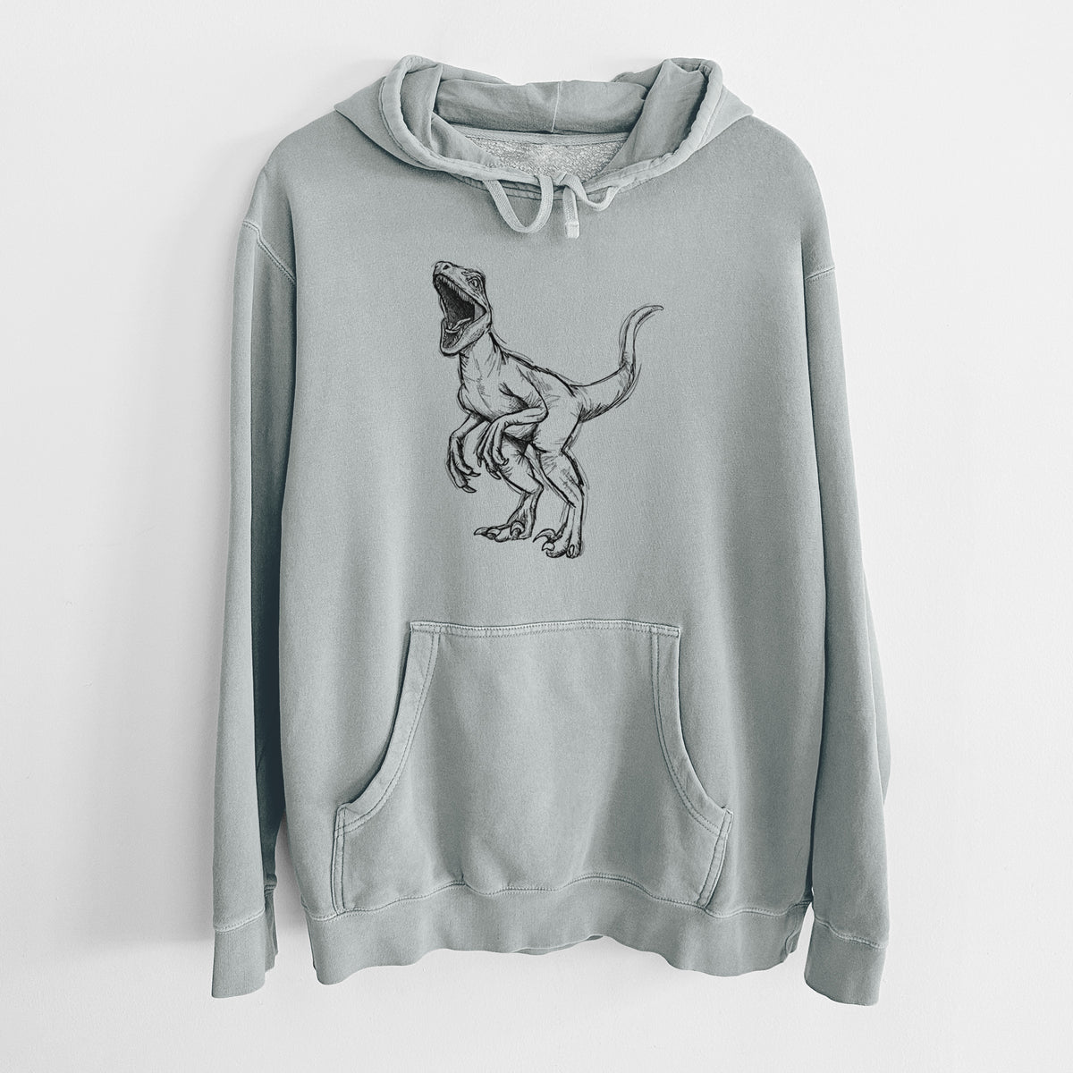 Sage green pigment dyed hoodie laid flat, printed with a black ink illustration of a Velociraptor roaring.