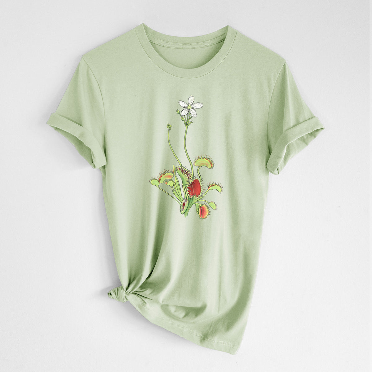 Spring green lightweight cotton t-shirt laid flat with the sleeves rolled, printed with a full-color illustration of a Venus flytrap plant with red traps and a small white flower.