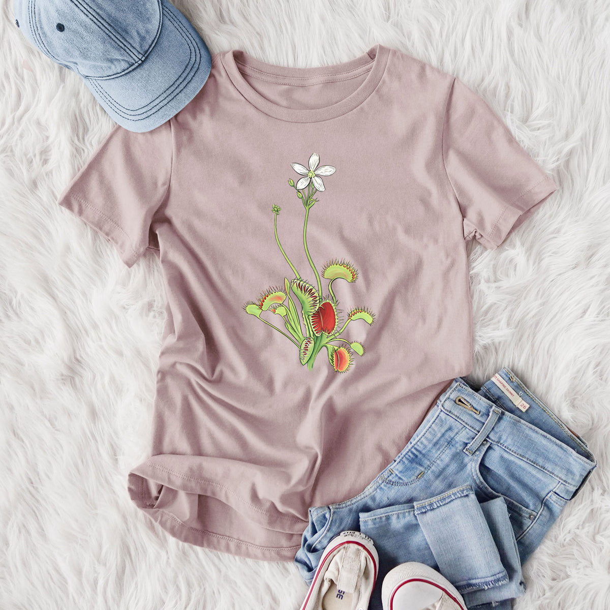 Women's relaxed fit cotton t-shirt printed with a full-color illustration of a Venus flytrap plant with red traps and a small white flower, styled flat on a white faux fur rug with jeans.