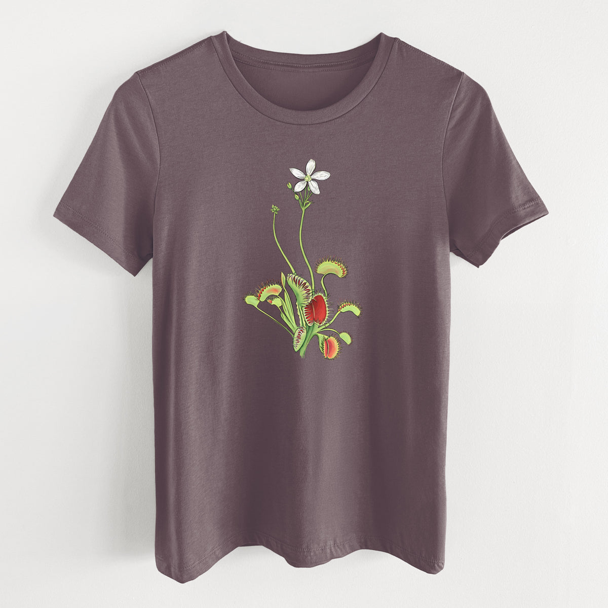 Purple storm women's relaxed fit cotton t-shirt laid flat, printed with a full-color illustration of a Venus flytrap plant with red traps and a small white flower.