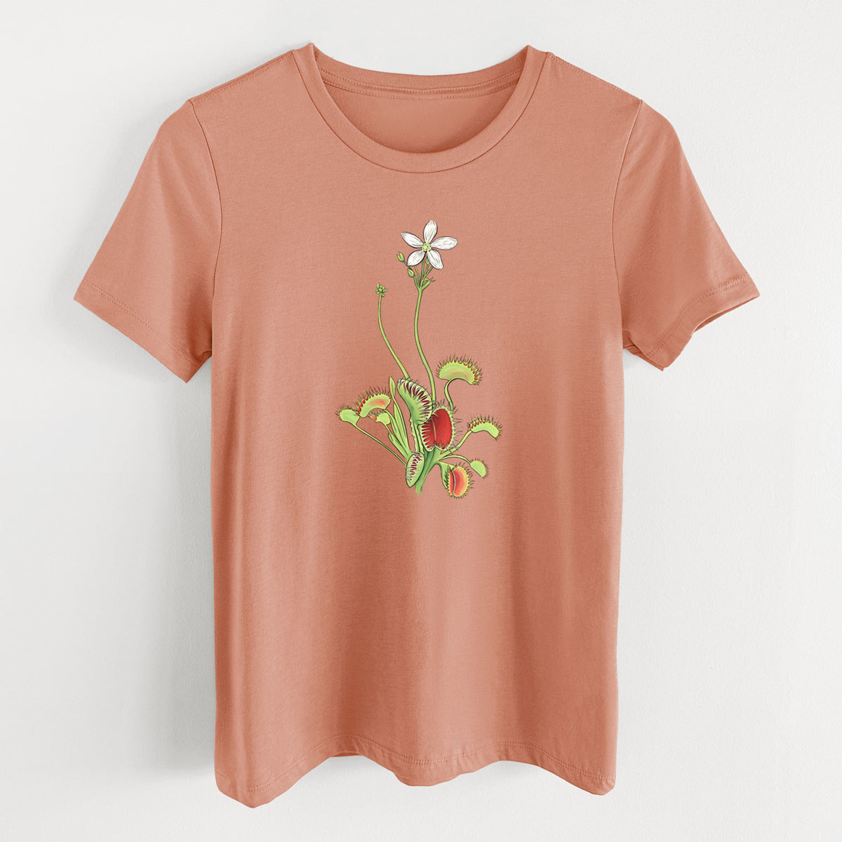 Terracotta orange women's relaxed fit cotton t-shirt laid flat, printed with a full-color illustration of a Venus flytrap plant with red traps and a small white flower.