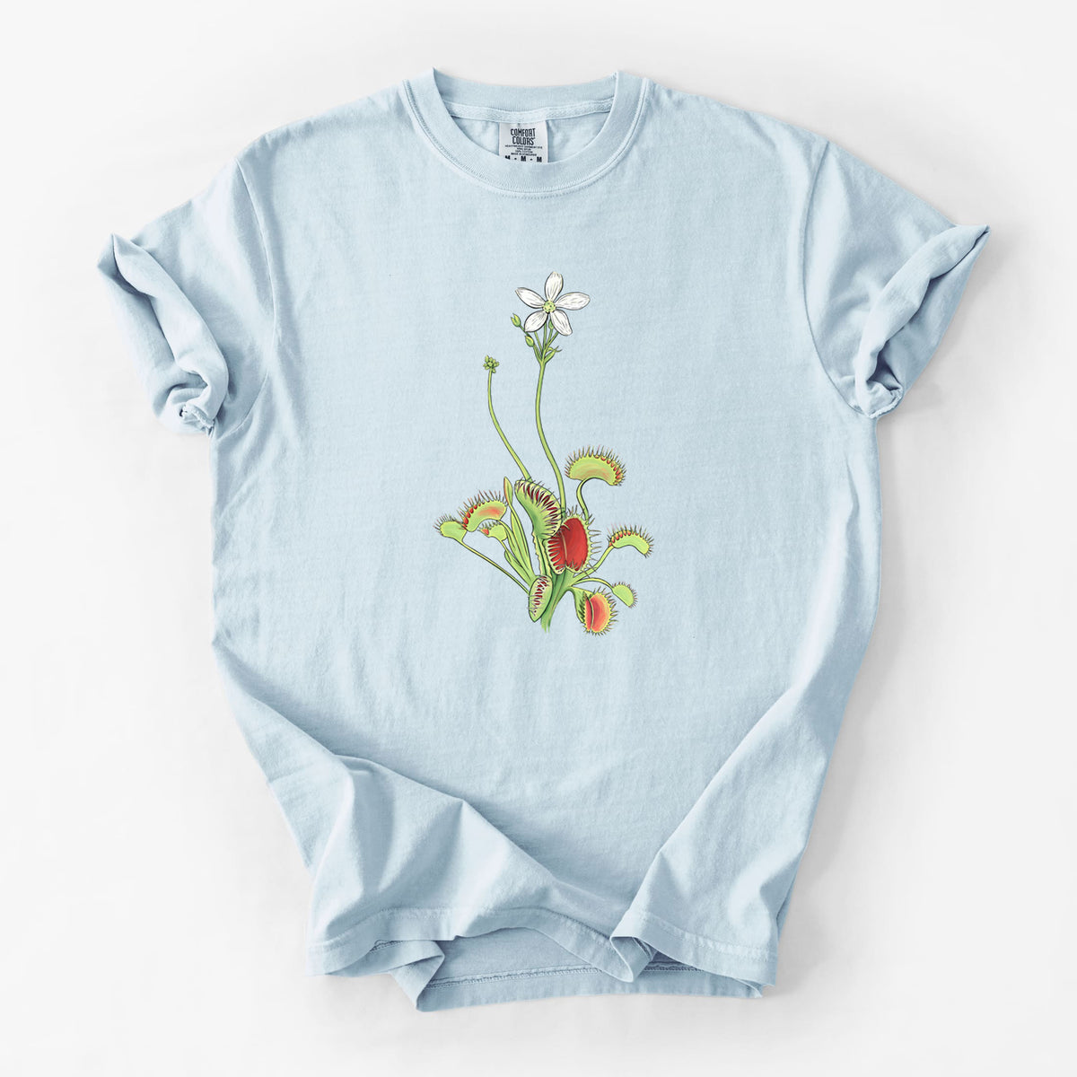 Chambray blue Comfort Colors t-shirt laid flat, printed with a full-color illustration of a Venus flytrap plant with red traps and a small white flower.