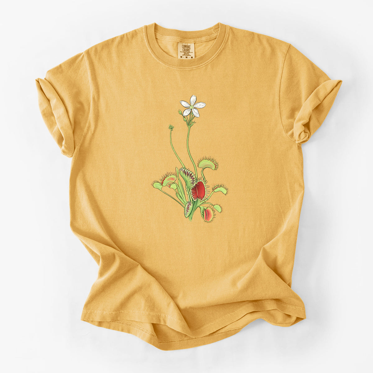 Golden wheat yellow Comfort Colors t-shirt laid flat, printed with a full-color illustration of a Venus flytrap plant with red traps and a small white flower.