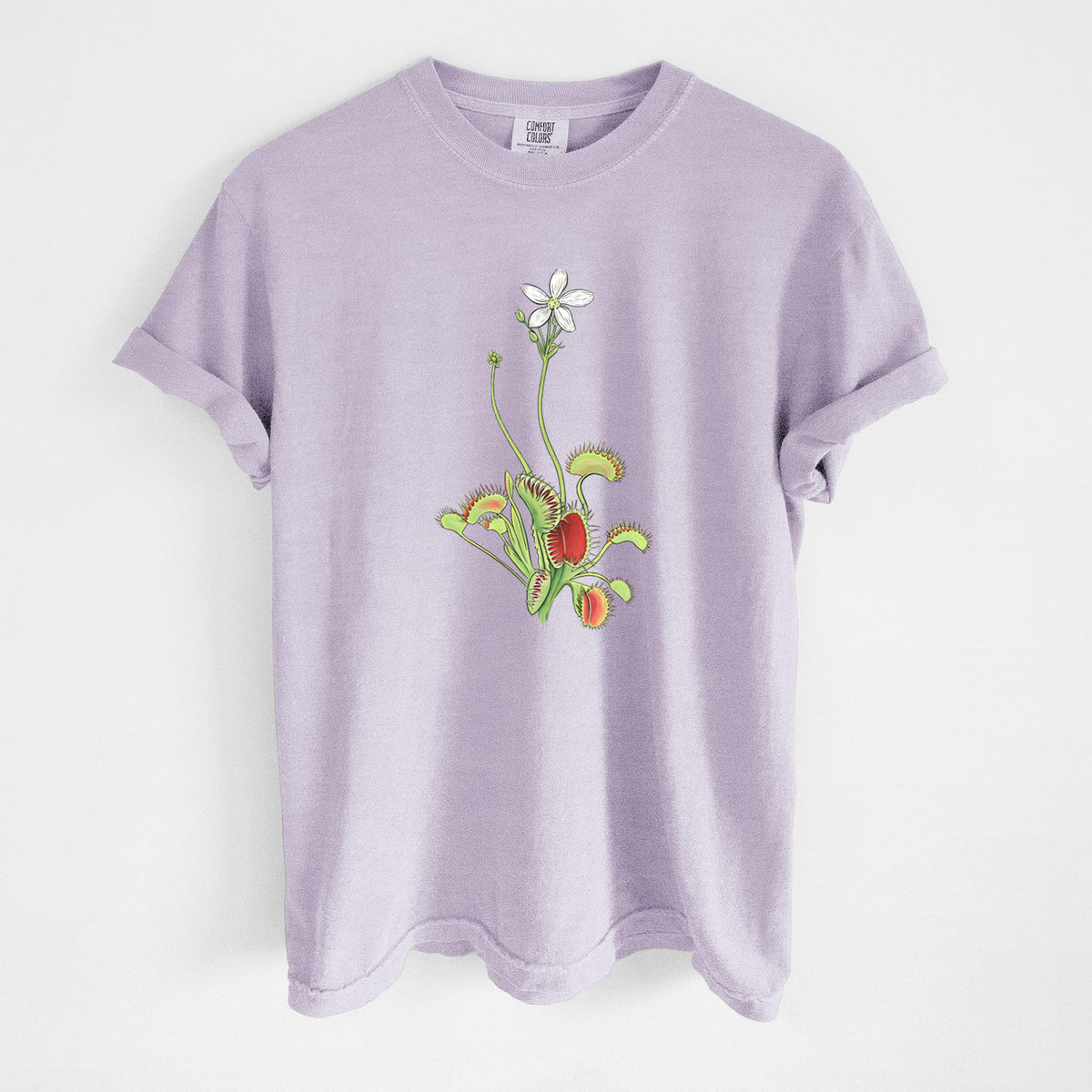Orchid purple Comfort Colors t-shirt laid flat, printed with a full-color illustration of a Venus flytrap plant with red traps and a small white flower.