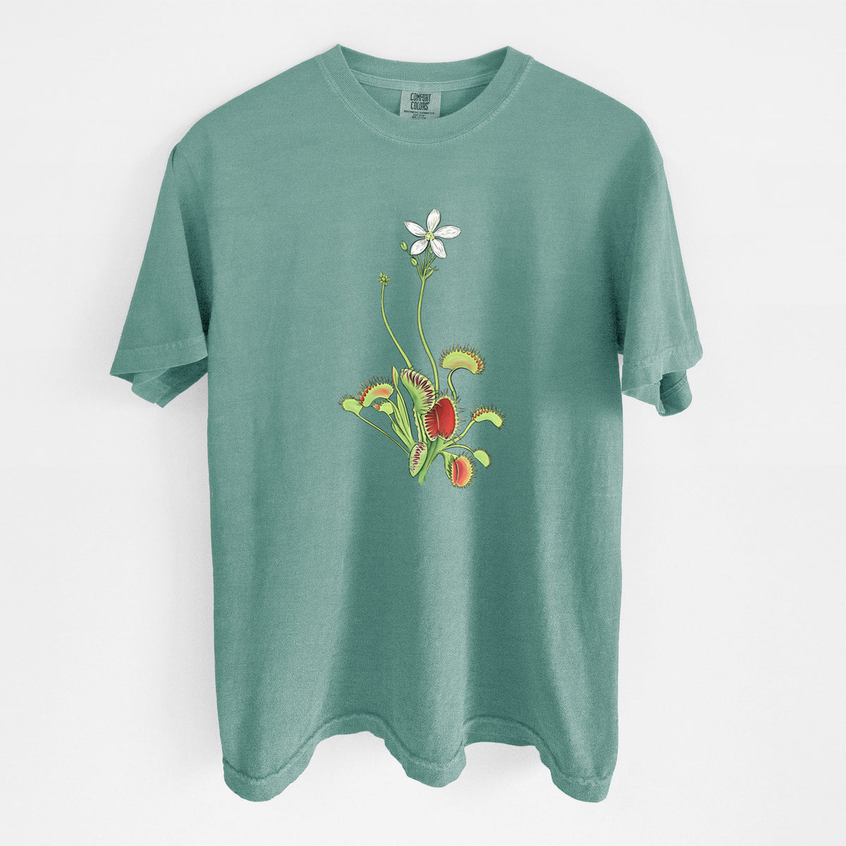 Reef green Comfort Colors t-shirt laid flat, printed with a full-color illustration of a Venus flytrap plant with red traps and a small white flower.