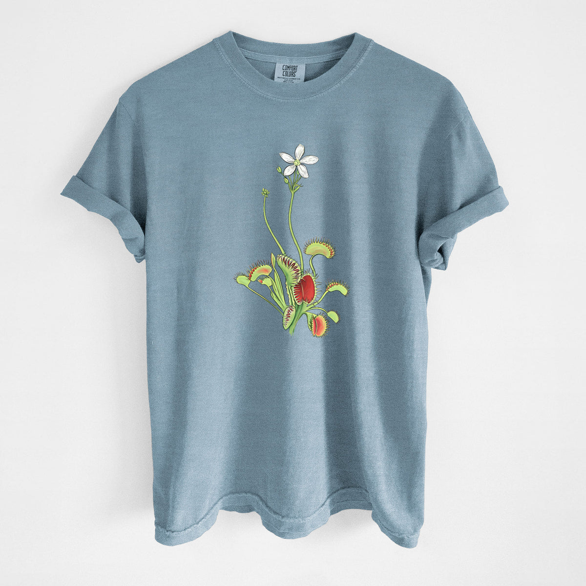 Steel blue Comfort Colors t-shirt laid flat, printed with a full-color illustration of a Venus flytrap plant with red traps and a small white flower.