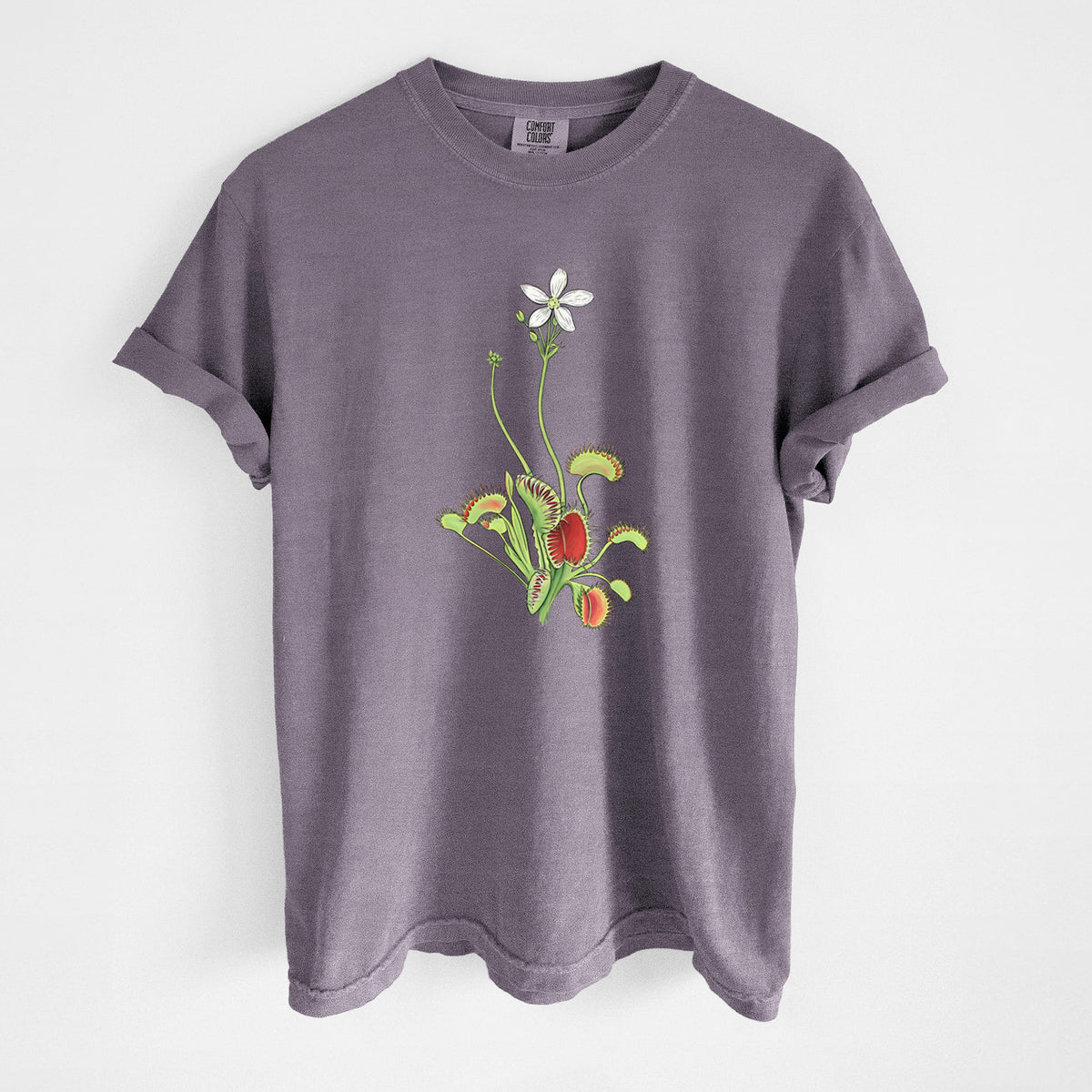 Wine red Comfort Colors t-shirt laid flat, printed with a full-color illustration of a Venus flytrap plant with red traps and a small white flower.