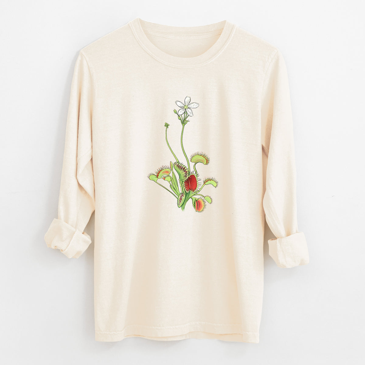 Ivory Comfort Colors long sleeve shirt laid flat with the cuffs rolled, printed with a full-color illustration of a Venus flytrap plant with red traps and a small white flower.